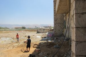 Children playing at the site of a substandard building occupied by refugee families in the Beqaa Valley, where exposed wiring, indoor use of diesel and wood burning stoves, lack of fire doors and household practices during renovation work combine to create a high level of fire risk.