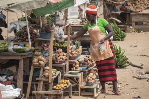 Mubende, Uganda - January 25th, 2020: Unidentified woman sells potatoes at a road market in Mubende, Uganda. Street markets play a significant role for local farmers.