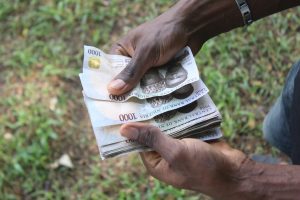 Young man Holding and Counting Nigeria 1000 Naira Note Currency Outdoor in Nigeria, West Africa Country