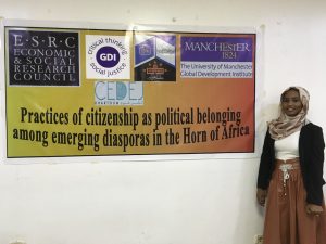 Researcher with sign saying 'practices of citizenship as political belonging among emerging diasporas in the Horn of Africa'